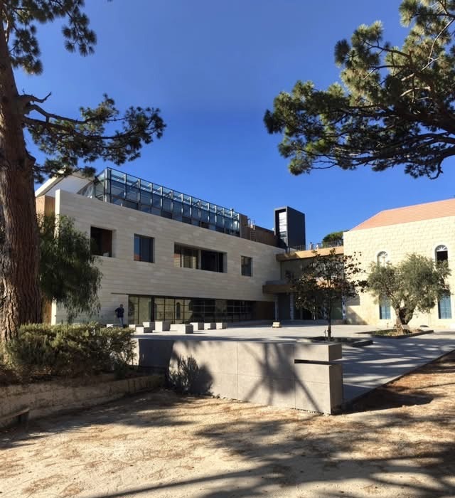 Le siège ECONOMA à Ebrine, parvis et façades en pierre sous les pins.