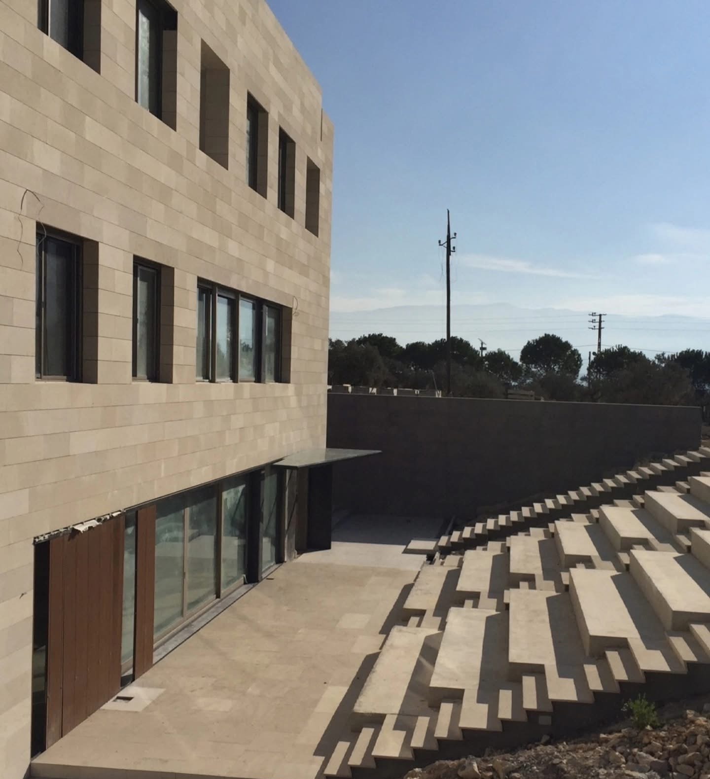 Le siège ECONOMA à Ebrine, façade en pierre et gradins extérieurs en cours d’achèvement.